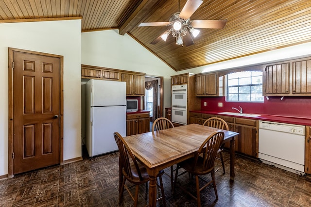 kitchen featuring brown cabinets, a sink, lofted ceiling with beams, white appliances, and a ceiling fan