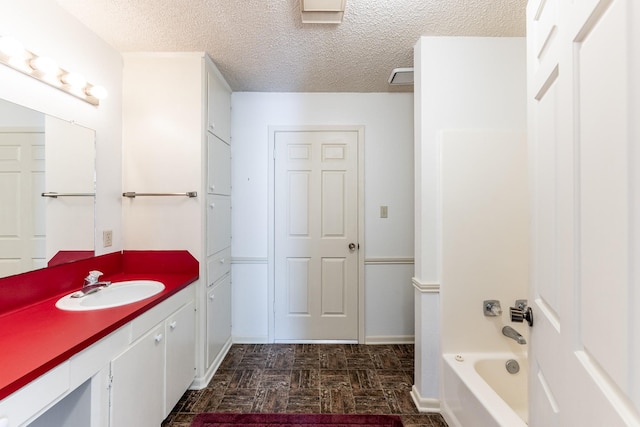 full bathroom featuring a textured ceiling and vanity