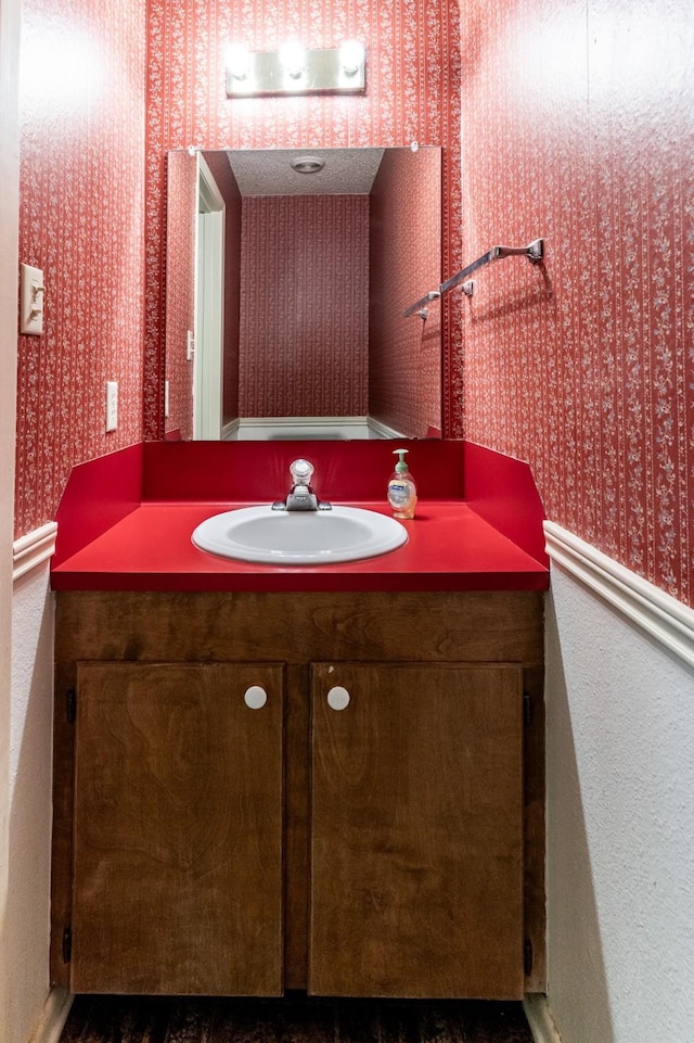 bathroom featuring vanity and wallpapered walls