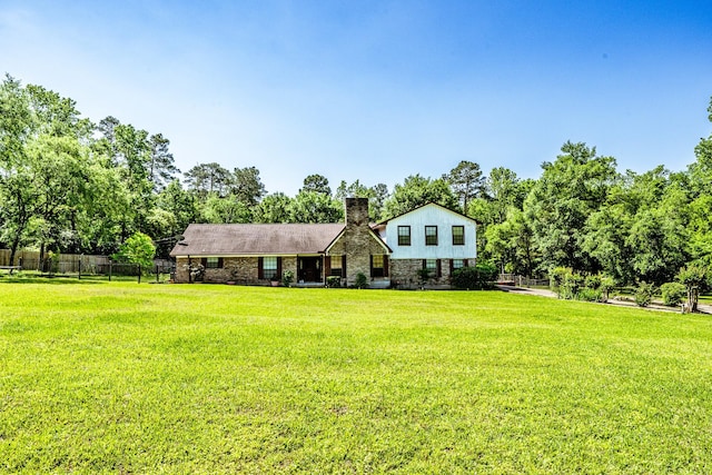 view of front of property featuring a chimney, fence, and a front lawn