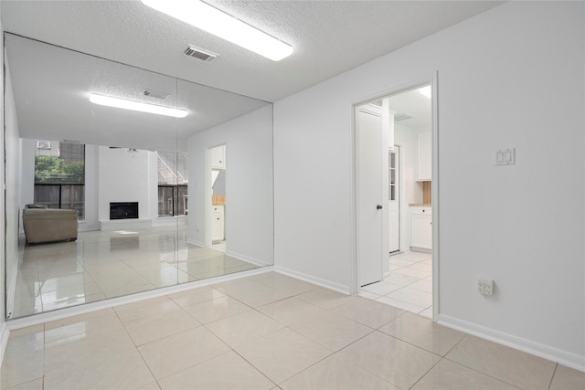 13742 Hollowgreen Dr Unit 604, Houston, TX 77082 - unfurnished room with a textured ceiling, light tile patterned floors, a fireplace, and baseboards
