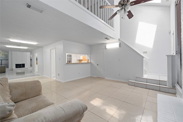13742 Hollowgreen Dr Unit 604, Houston, TX 77082 - unfurnished living room featuring ceiling fan, tile patterned flooring, baseboards, a towering ceiling, and a fireplace with raised hearth