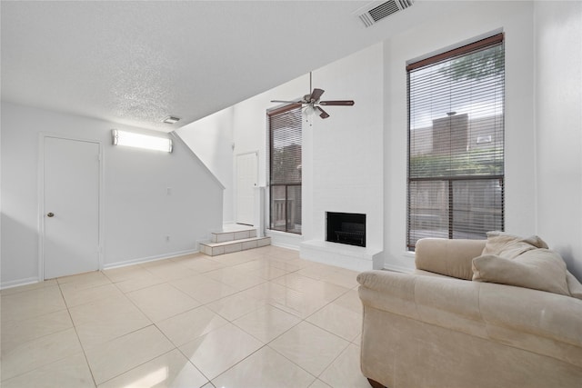 13742 Hollowgreen Dr Unit 604, Houston, TX 77082 - living room featuring light tile patterned floors, ceiling fan, a textured ceiling, a large fireplace, and baseboards