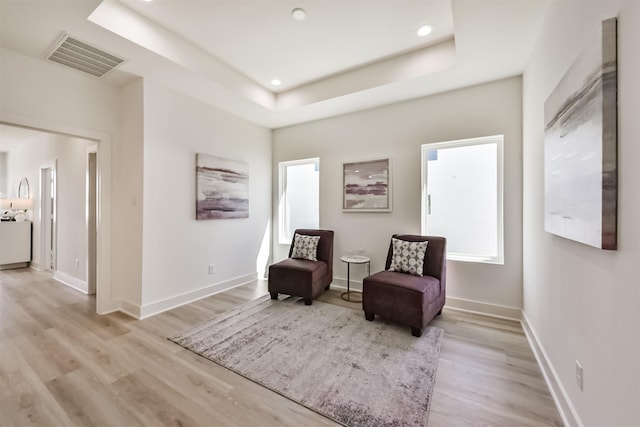 sitting room featuring a raised ceiling, light wood finished floors, recessed lighting, baseboards, and visible vents