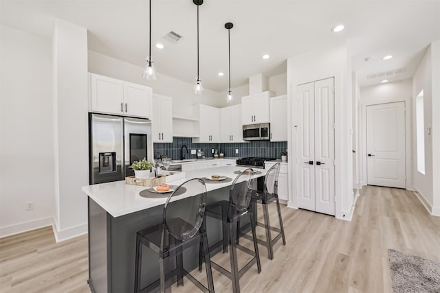 kitchen with light countertops, stainless steel appliances, visible vents, and white cabinetry