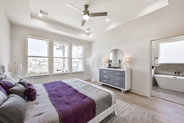bedroom featuring visible vents, baseboards, light wood-style floors, a tray ceiling, and recessed lighting