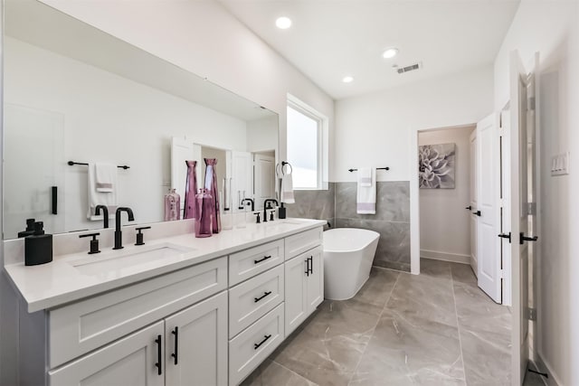 full bathroom featuring a sink, a freestanding bath, double vanity, and visible vents