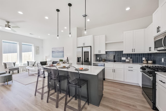 kitchen featuring visible vents, open shelves, a sink, light wood finished floors, and appliances with stainless steel finishes