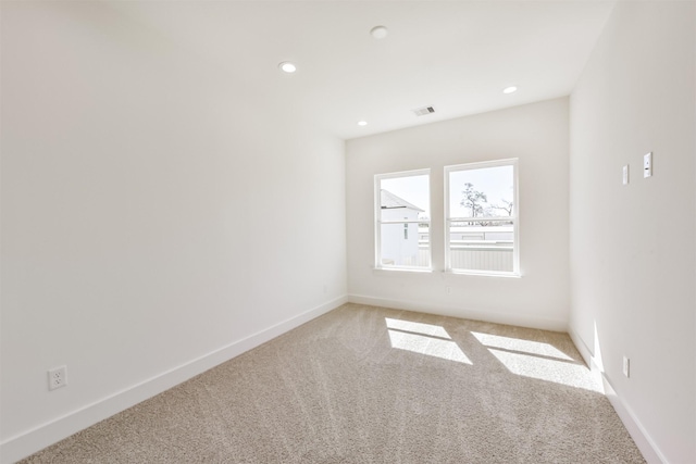 empty room featuring baseboards, recessed lighting, visible vents, and light carpet