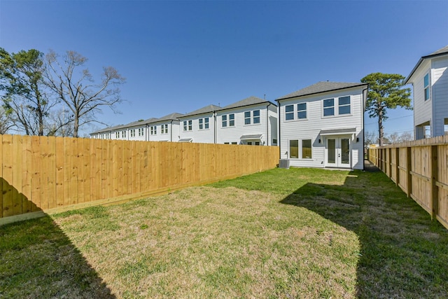 back of property featuring a lawn, a fenced backyard, french doors, and a residential view