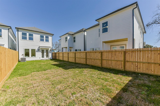 rear view of house with a lawn, cooling unit, french doors, and a fenced backyard