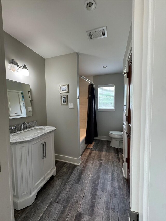 full bathroom featuring toilet, wood finished floors, vanity, visible vents, and baseboards