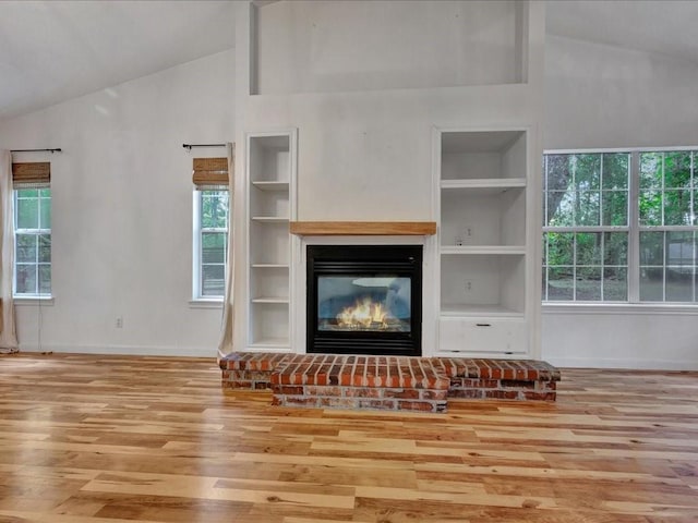 unfurnished living room featuring baseboards, wood finished floors, built in features, and a fireplace