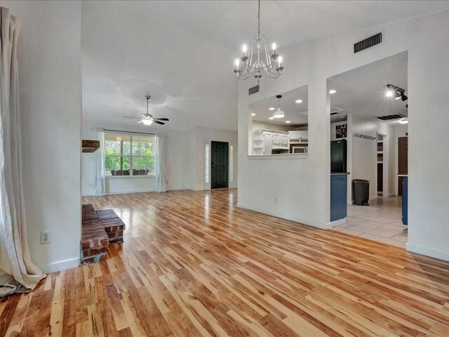 unfurnished living room with visible vents, light wood-type flooring, baseboards, and ceiling fan with notable chandelier