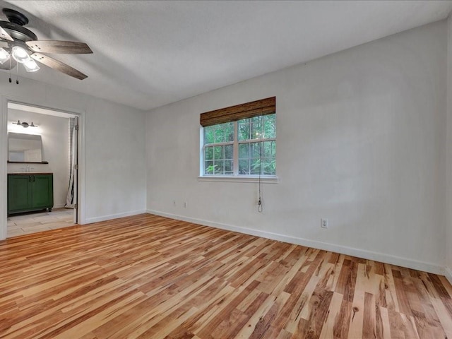 spare room featuring ceiling fan, baseboards, and light wood-style floors