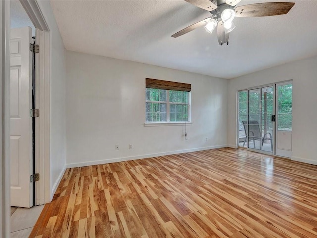unfurnished room with light wood finished floors, a ceiling fan, a textured ceiling, and baseboards