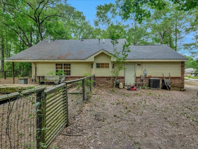 back of property featuring fence, roof with shingles, cooling unit, and brick siding