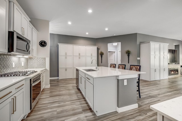 14302 Winema View Ln, Conroe, TX 77384 - kitchen with a sink, appliances with stainless steel finishes, light wood-style floors, recessed lighting, and tasteful backsplash