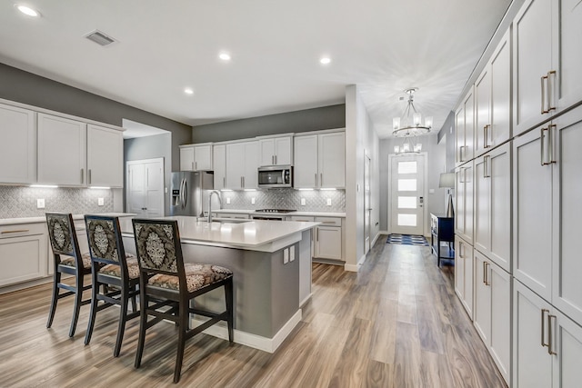 14302 Winema View Ln, Conroe, TX 77384 - kitchen with appliances with stainless steel finishes, a sink, light countertops, decorative backsplash, and a kitchen bar