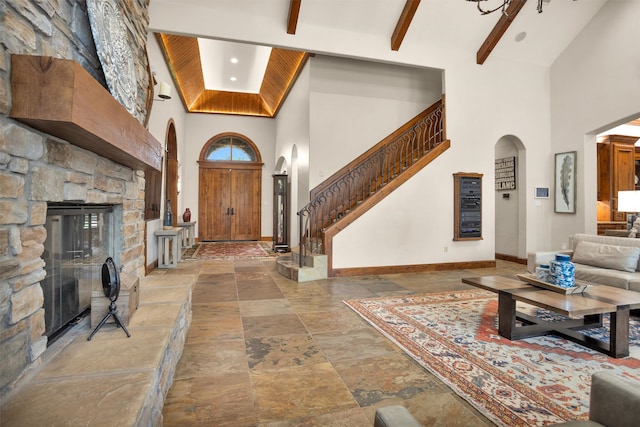 foyer entrance with a high ceiling, arched walkways, stone tile floors, stairs, and baseboards