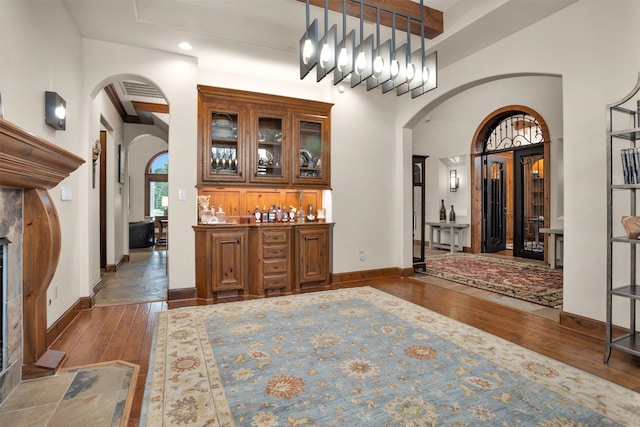 foyer with arched walkways, baseboards, wood-type flooring, and beam ceiling
