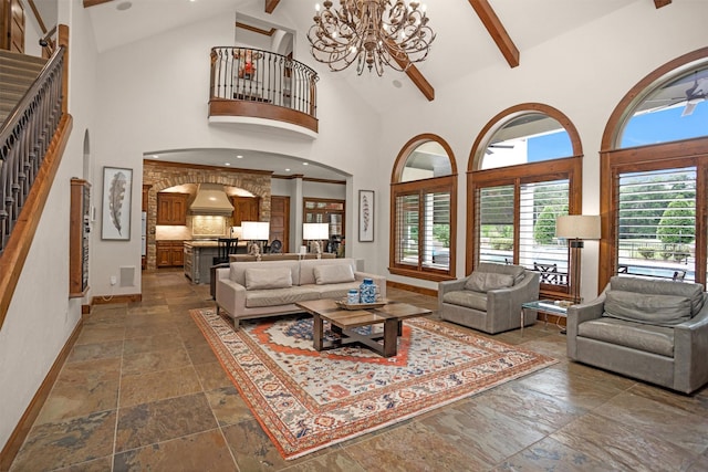 living area featuring stone tile floors, high vaulted ceiling, plenty of natural light, and baseboards