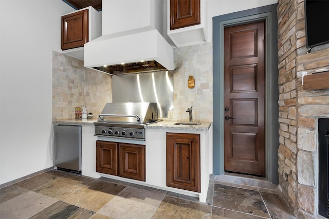 kitchen featuring a sink, custom exhaust hood, fridge, and stone tile floors