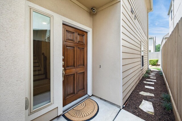 property entrance with fence and stucco siding