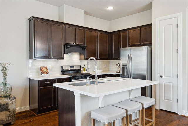 kitchen with light countertops, under cabinet range hood, stainless steel appliances, and a sink