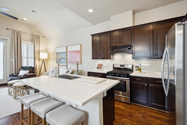 kitchen featuring dark wood-style flooring, a sink, appliances with stainless steel finishes, under cabinet range hood, and visible vents