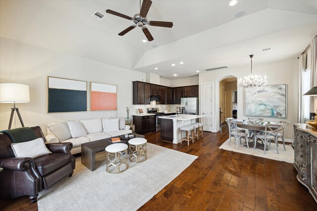 living area featuring vaulted ceiling, ceiling fan with notable chandelier, arched walkways, dark wood-type flooring, and visible vents