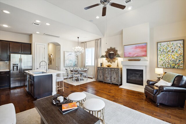 living area featuring ceiling fan with notable chandelier, arched walkways, dark wood-style flooring, visible vents, and recessed lighting