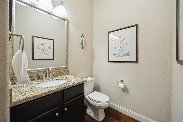 bathroom featuring baseboards, toilet, vanity, and wood finished floors