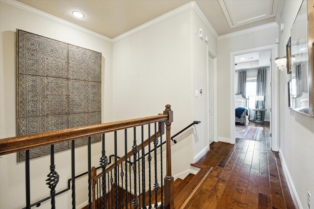 hallway with attic access, dark wood-style floors, baseboards, an upstairs landing, and crown molding