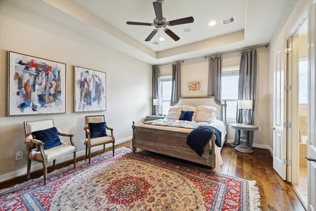 bedroom with hardwood / wood-style flooring, a tray ceiling, baseboards, visible vents, and recessed lighting