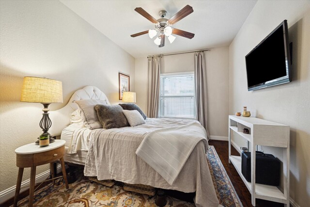 bedroom featuring baseboards, ceiling fan, and dark wood-style flooring