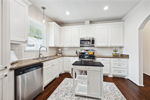 701 Coronado St, Houston, TX 77009 - kitchen featuring stainless steel appliances, a sink, arched walkways, white cabinets, and backsplash