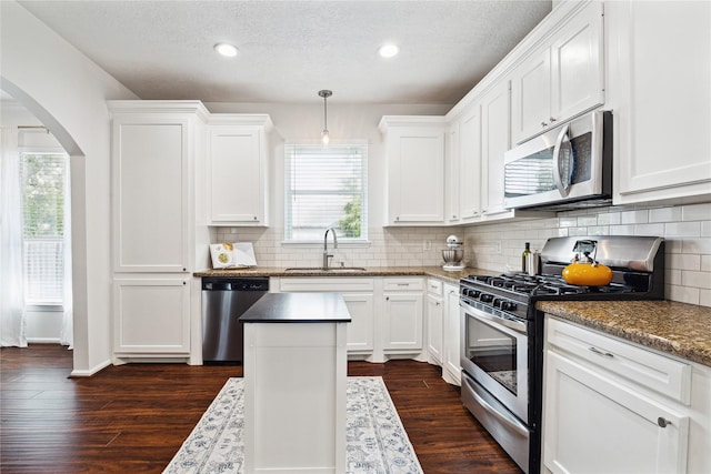 701 Coronado St, Houston, TX 77009 - kitchen featuring stainless steel appliances, a sink, arched walkways, white cabinets, and recessed lighting