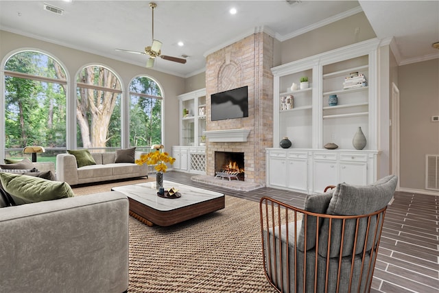 living area with crown molding, a fireplace, a ceiling fan, and visible vents
