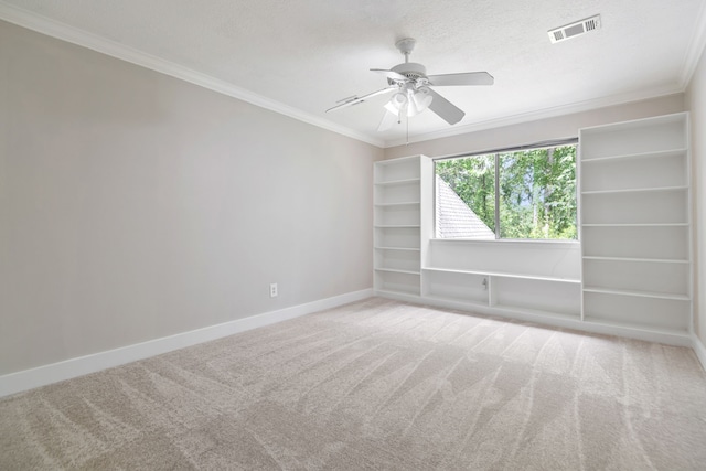 spare room featuring crown molding, baseboards, ceiling fan, and visible vents