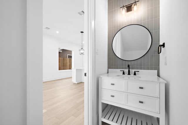 bathroom featuring vanity, wood finished floors, visible vents, and tile walls