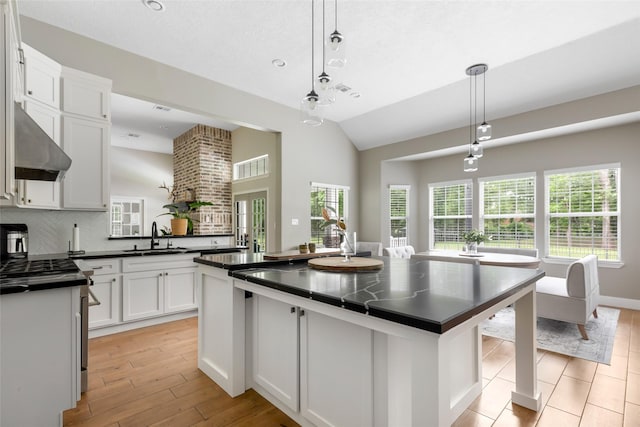 8118 S Laura Cir, Baytown, TX 77521 - kitchen featuring light wood-style flooring, exhaust hood, a sink, white cabinetry, and dark countertops