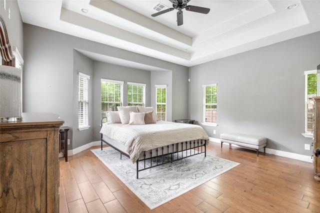 8118 S Laura Cir, Baytown, TX 77521 - bedroom featuring multiple windows, light wood-style flooring, and a raised ceiling