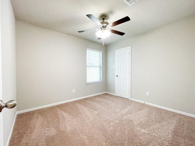 spare room with baseboards, ceiling fan, and light colored carpet