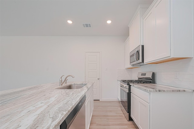 17722 Pamukkale Pl, Tomball, TX 77377 - kitchen featuring stainless steel appliances, a sink, white cabinets, light stone countertops, and recessed lighting