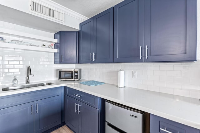 6300 Seawall Blvd Unit 3225, Galveston, TX 77551 - kitchen with visible vents, blue cabinets, a sink, stainless steel microwave, and tasteful backsplash