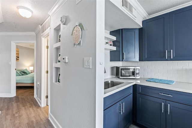 6300 Seawall Blvd Unit 3225, Galveston, TX 77551 - kitchen featuring open shelves, a textured ceiling, blue cabinets, light countertops, and stainless steel microwave
