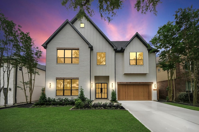 view of front facade with a front yard, driveway, board and batten siding, brick siding, and an attached garage