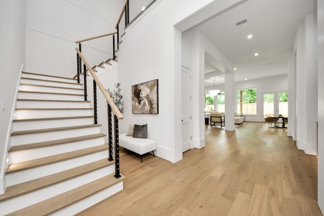 foyer with light wood finished floors, recessed lighting, stairs, visible vents, and baseboards