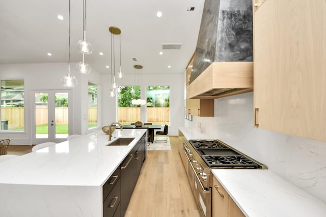kitchen featuring recessed lighting, custom exhaust hood, light wood-style flooring, a large island, and a sink